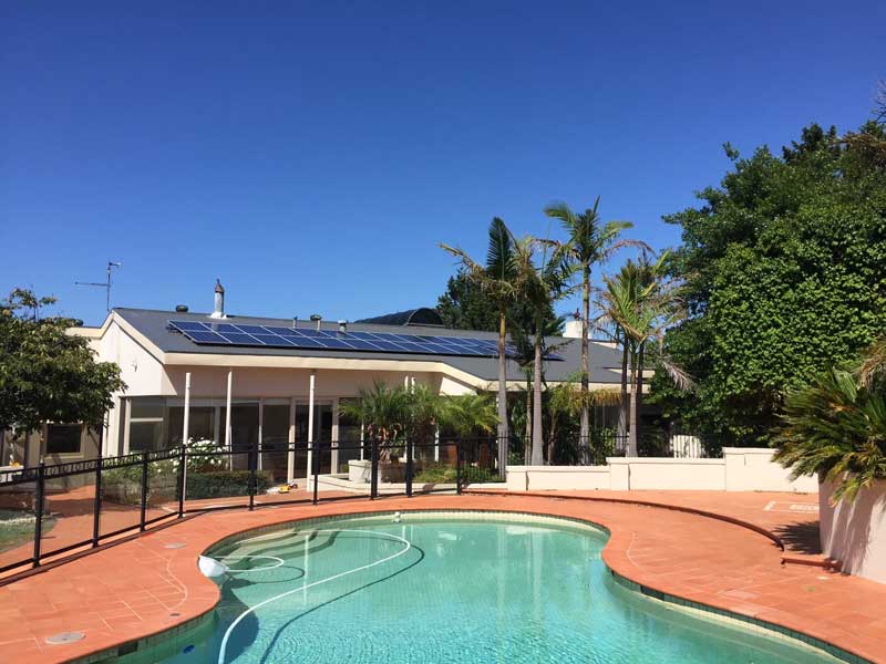 Solar panels installed on roof of home next to outdoor pool